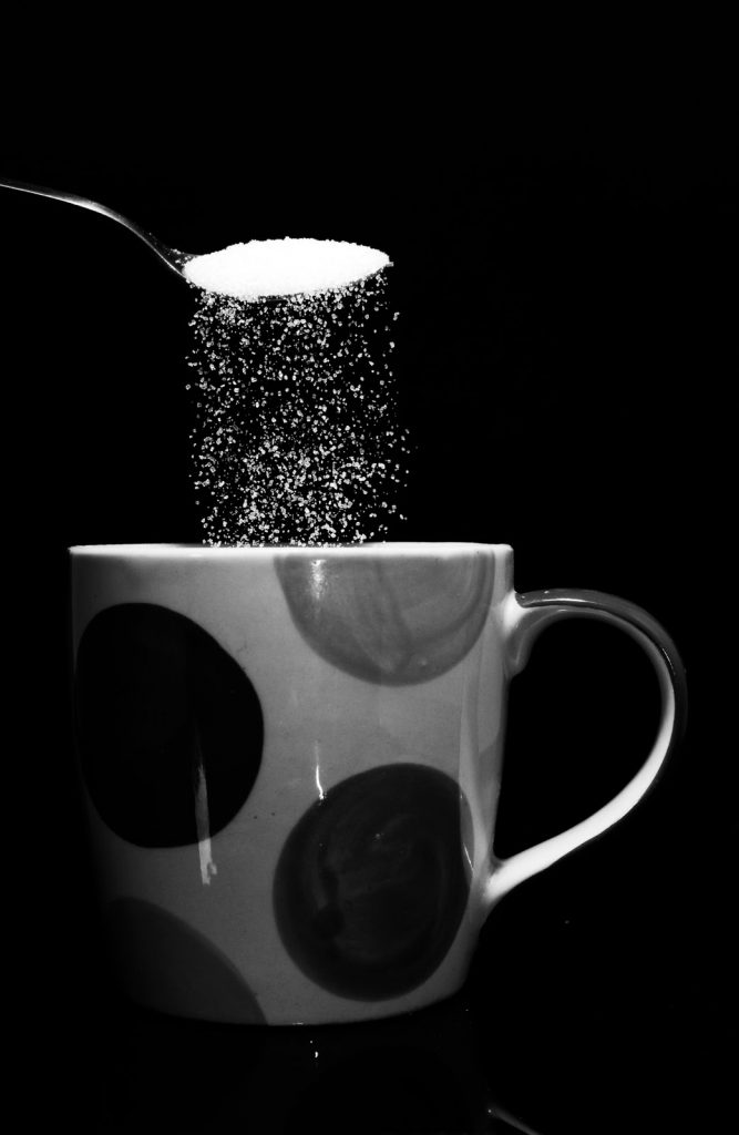 spoonful of sugar being tipped into cup