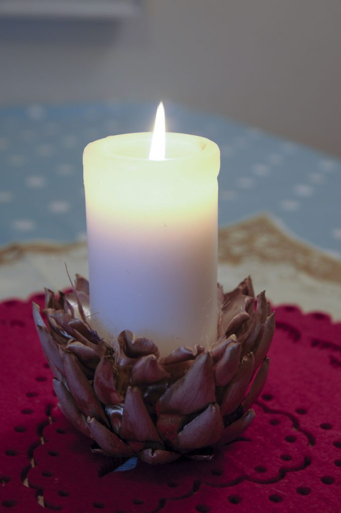 Sticking candles into artichoke seed heads for unique, homemade festive decorations